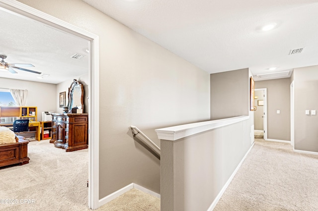 hall featuring an upstairs landing, visible vents, carpet floors, and baseboards