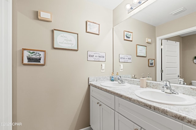 bathroom featuring double vanity, visible vents, and a sink