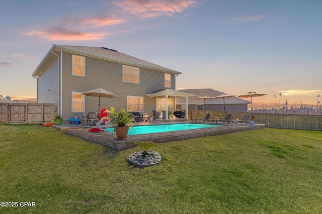 back of property at dusk with a patio area, a lawn, and a fenced backyard