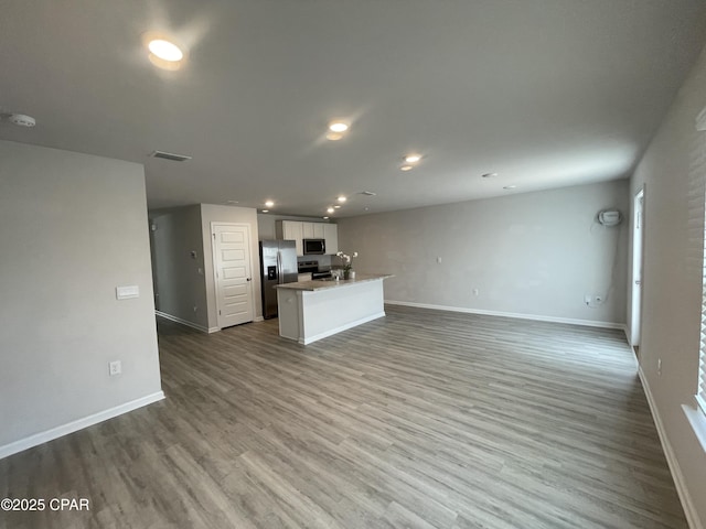 unfurnished living room featuring baseboards, visible vents, wood finished floors, and recessed lighting