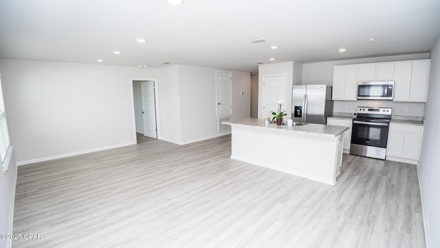 kitchen featuring a center island, appliances with stainless steel finishes, white cabinets, light wood-type flooring, and baseboards