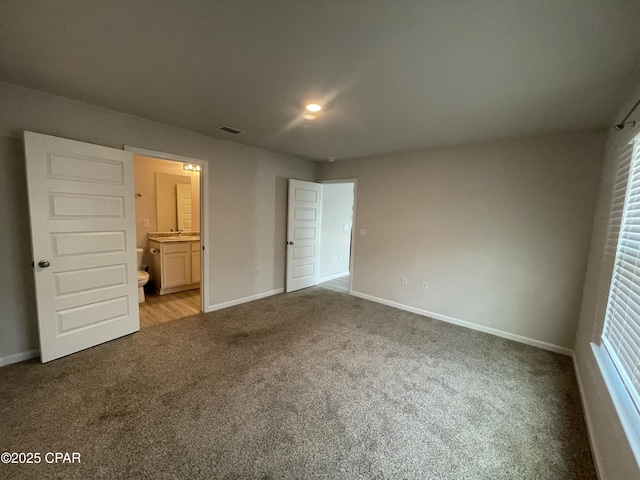 unfurnished bedroom with carpet, a sink, visible vents, and baseboards