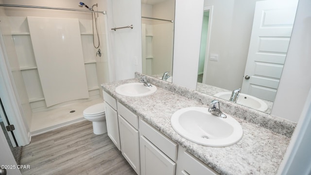 full bathroom featuring wood finished floors, a stall shower, and a sink