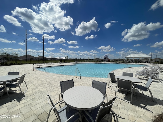 pool with fence, outdoor dining area, and a patio