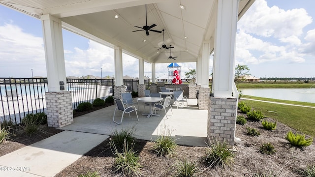 view of patio / terrace featuring a water view, fence, outdoor dining area, and a ceiling fan