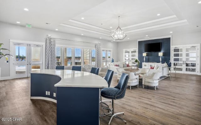 dining area featuring recessed lighting, wood finished floors, french doors, a raised ceiling, and an inviting chandelier