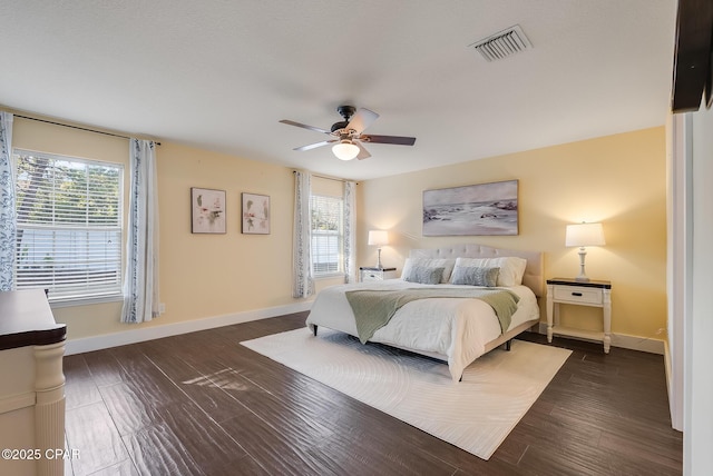 bedroom with multiple windows, dark wood finished floors, visible vents, and baseboards