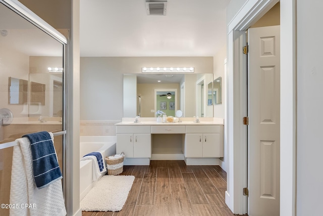 bathroom with wood finished floors, vanity, visible vents, a shower stall, and a bath