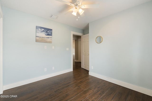 spare room featuring visible vents, dark wood finished floors, a ceiling fan, and baseboards