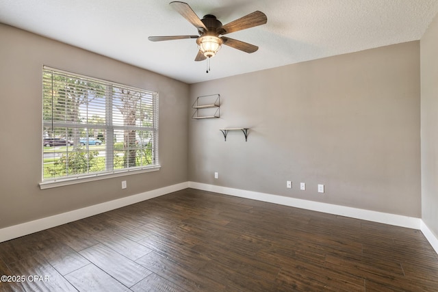 spare room featuring a textured ceiling, dark wood-type flooring, plenty of natural light, and baseboards