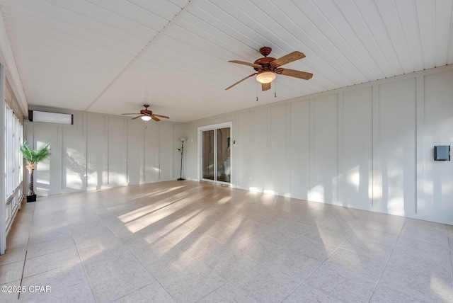 spare room with light tile patterned floors, ceiling fan, and a decorative wall