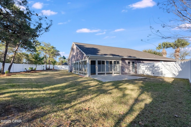 rear view of house featuring a lawn, a patio, a sunroom, a fenced backyard, and roof with shingles