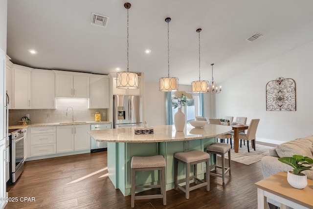 kitchen with backsplash, visible vents, stainless steel appliances, and a sink