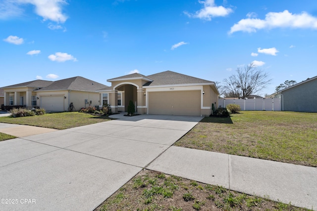 view of front of property with stucco siding, a front lawn, an attached garage, and fence