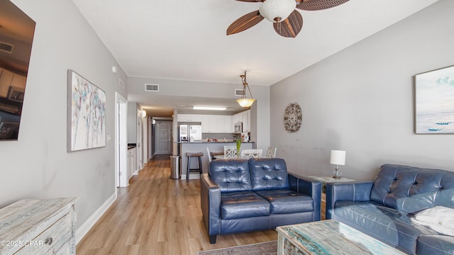 living room with visible vents, baseboards, a ceiling fan, and light wood finished floors