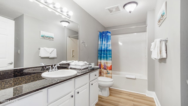 bathroom featuring visible vents, shower / bathtub combination with curtain, toilet, wood finished floors, and vanity