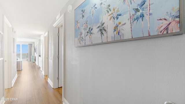 corridor featuring baseboards and wood finished floors