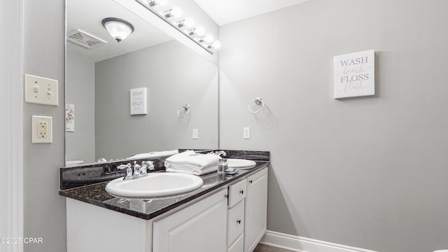 bathroom featuring a sink, visible vents, baseboards, and double vanity