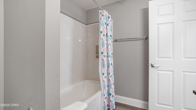 bathroom with shower / bathtub combination with curtain, baseboards, and wood finished floors