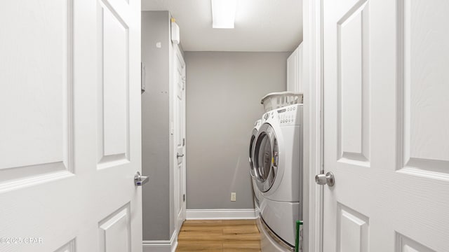 washroom with baseboards, washer / clothes dryer, laundry area, and light wood finished floors