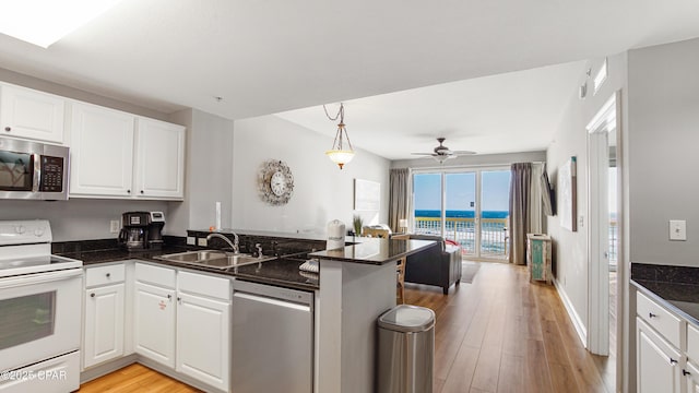 kitchen with light wood-type flooring, a sink, stainless steel appliances, a peninsula, and white cabinets