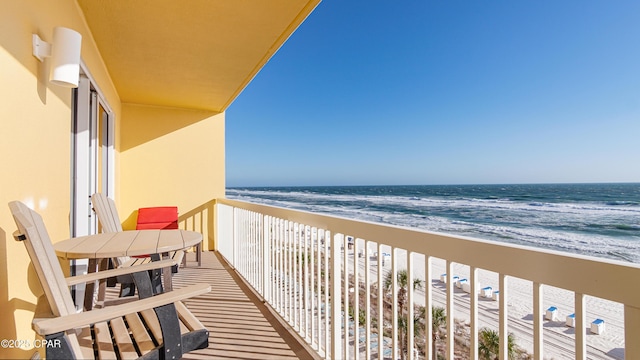 balcony with a water view and a view of the beach