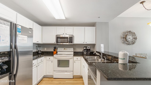 kitchen with a sink, a peninsula, white cabinets, and stainless steel appliances