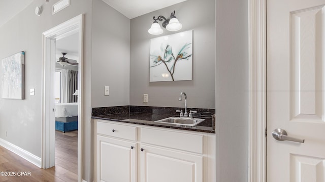 ensuite bathroom featuring visible vents, a ceiling fan, ensuite bath, wood finished floors, and vanity