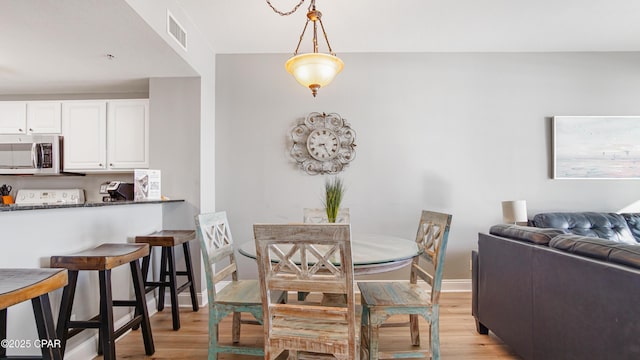 dining area featuring visible vents, light wood-type flooring, and baseboards