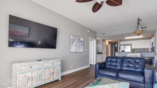 living area with visible vents, baseboards, a ceiling fan, and wood finished floors