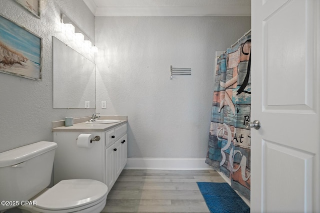 bathroom with crown molding, toilet, a textured wall, wood finished floors, and vanity