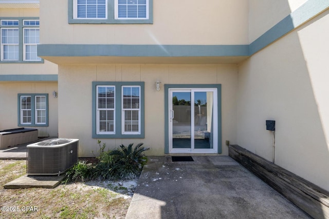 entrance to property featuring central air condition unit, a patio, visible vents, and stucco siding