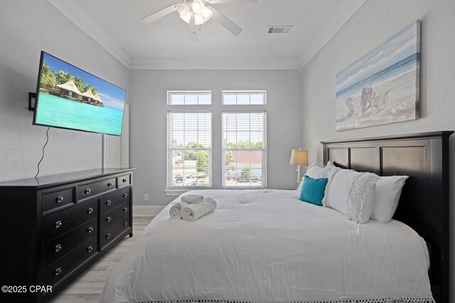 bedroom with visible vents, ceiling fan, light wood-style floors, and ornamental molding