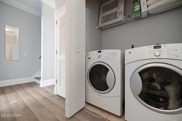 laundry room with baseboards, light wood-style floors, ornamental molding, and washing machine and clothes dryer