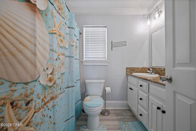 full bathroom with toilet, wood finished floors, crown molding, baseboards, and vanity