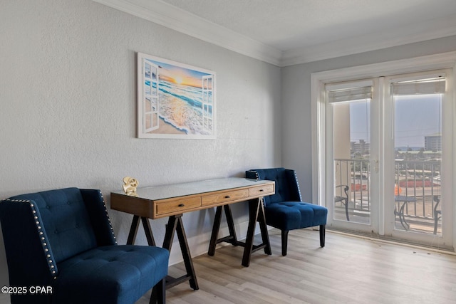 living area featuring light wood-style flooring, a healthy amount of sunlight, ornamental molding, and a textured wall