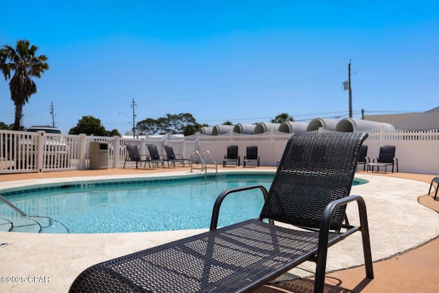 community pool with a patio area and fence