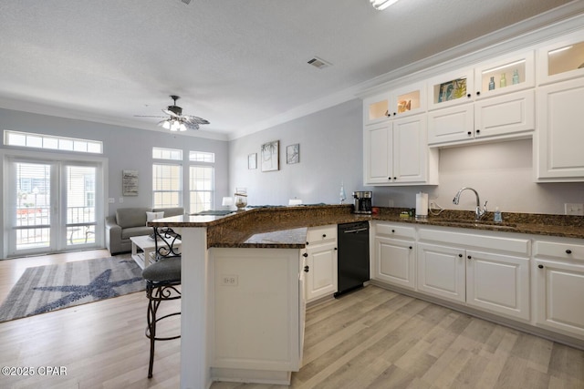 kitchen with a breakfast bar area, a peninsula, a sink, open floor plan, and light wood-type flooring