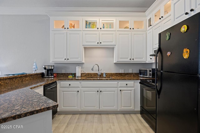 kitchen with black appliances, white cabinets, light wood finished floors, and a sink