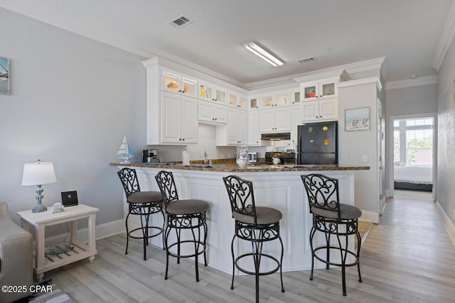 kitchen featuring visible vents, crown molding, a breakfast bar area, and freestanding refrigerator