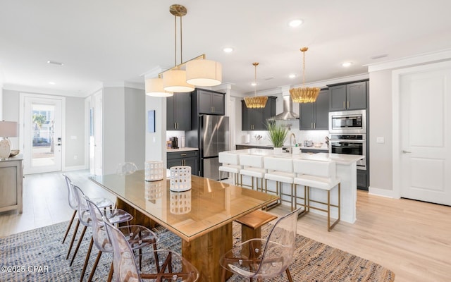 dining room featuring ornamental molding, recessed lighting, light wood-style floors, and baseboards