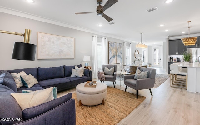 living room with ornamental molding, recessed lighting, visible vents, and light wood-style floors