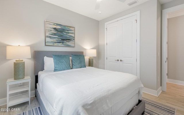 bedroom with light wood-style flooring, a ceiling fan, visible vents, baseboards, and a closet