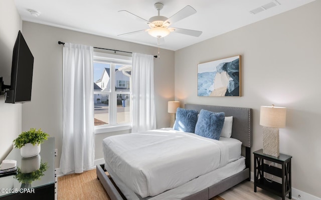 bedroom with light wood-type flooring, visible vents, ceiling fan, and baseboards