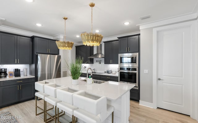 kitchen featuring visible vents, appliances with stainless steel finishes, a breakfast bar, light stone counters, and wall chimney range hood