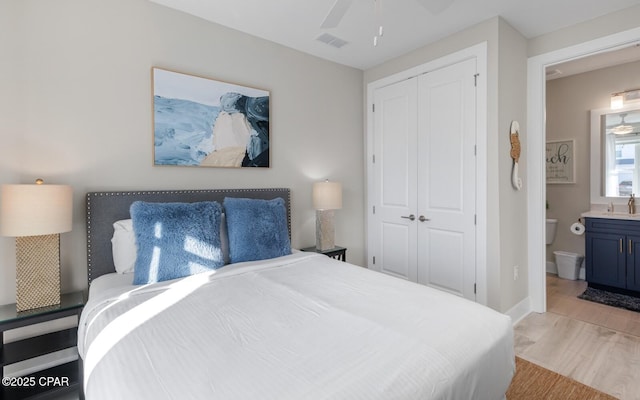 bedroom with a sink, visible vents, baseboards, light wood-style floors, and a closet