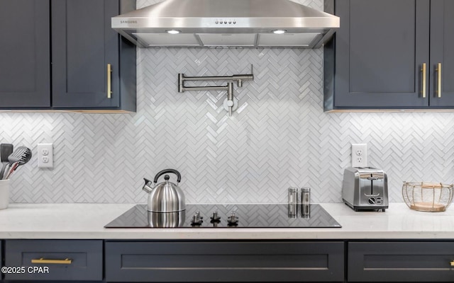 kitchen featuring black electric stovetop, light countertops, blue cabinetry, and extractor fan