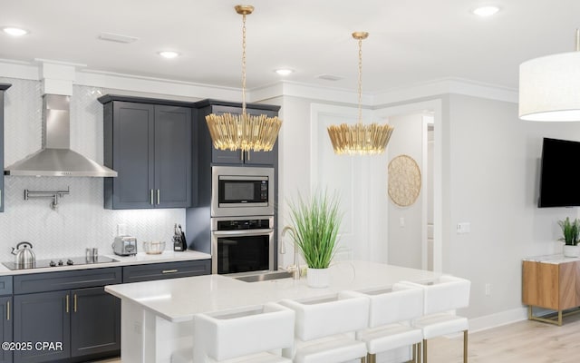 kitchen with decorative backsplash, wall chimney exhaust hood, a breakfast bar, stainless steel appliances, and light countertops