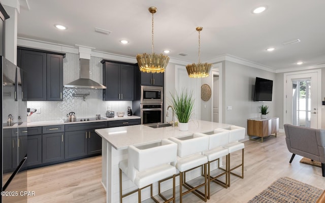 kitchen featuring decorative backsplash, appliances with stainless steel finishes, ornamental molding, a sink, and wall chimney exhaust hood