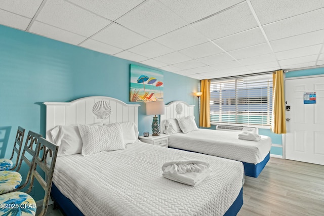 bedroom with a paneled ceiling, baseboards, and wood finished floors